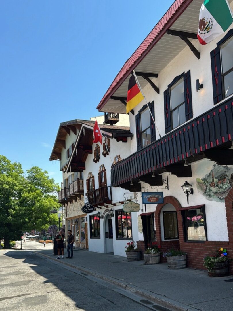 A charming Bavarian-style building with flags on a sunny day.