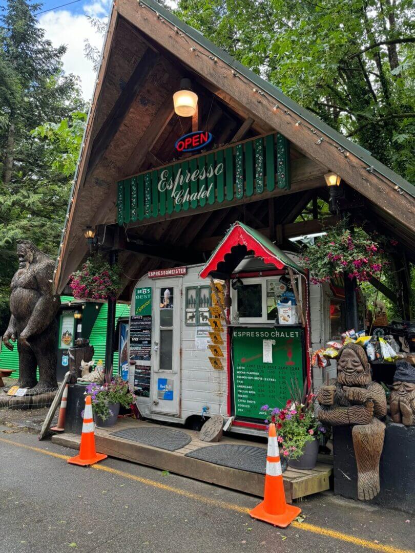 Small wooden kiosk in a lush forest setting with elephant statues nearby.