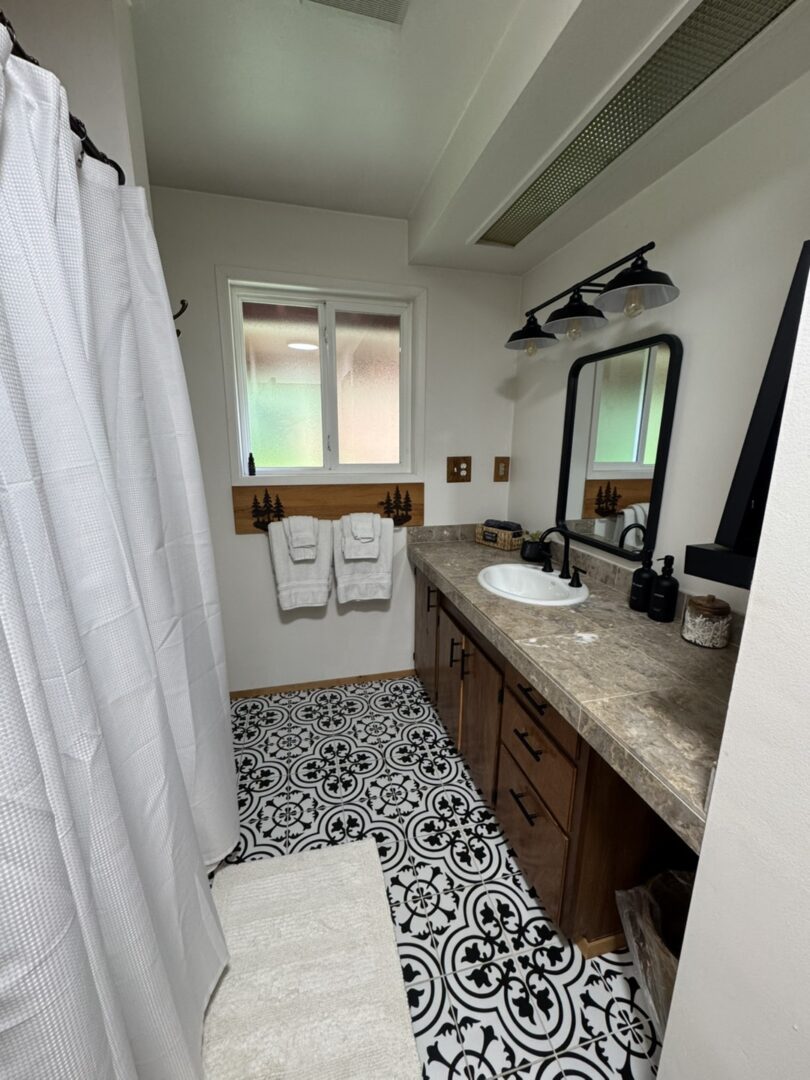 Bright bathroom with patterned tile and wooden vanity under dual sinks.