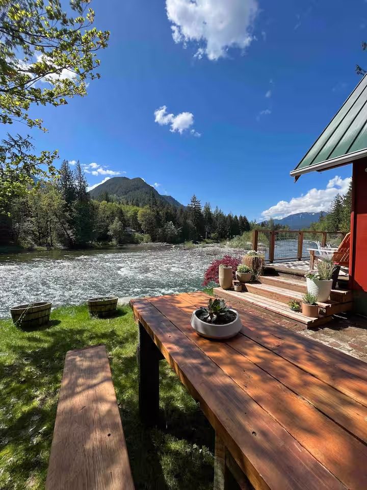 Peaceful river view from a wooden deck with mountains in the background.
