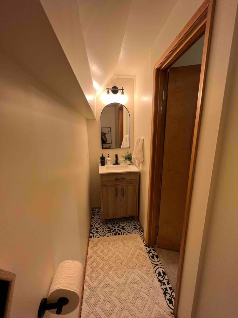 Narrow bathroom hallway with wooden cabinet and mirror.