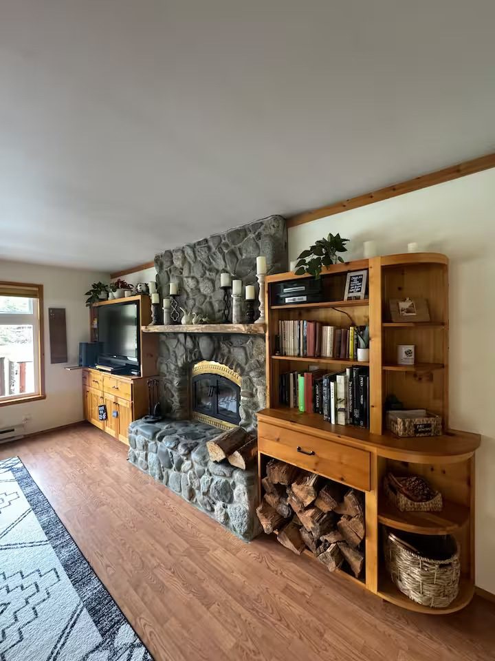 Cozy living room with stone fireplace and wooden shelves.