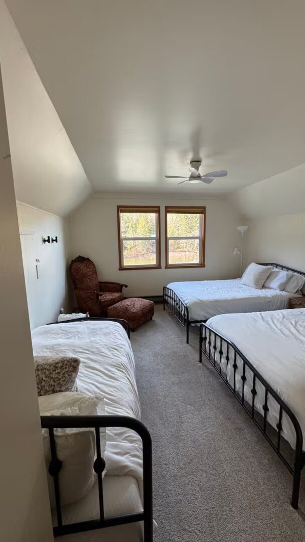 Cozy bedroom with two double beds and a single bed near a window.