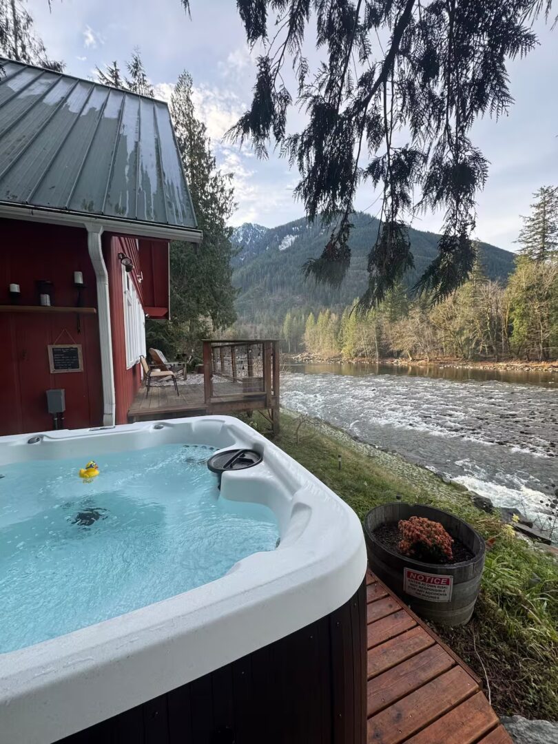 Hot tub on a deck overlooking a river and mountains.