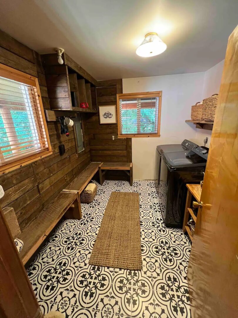 Cozy rustic laundry room with wood paneling and patterned floor tiles.