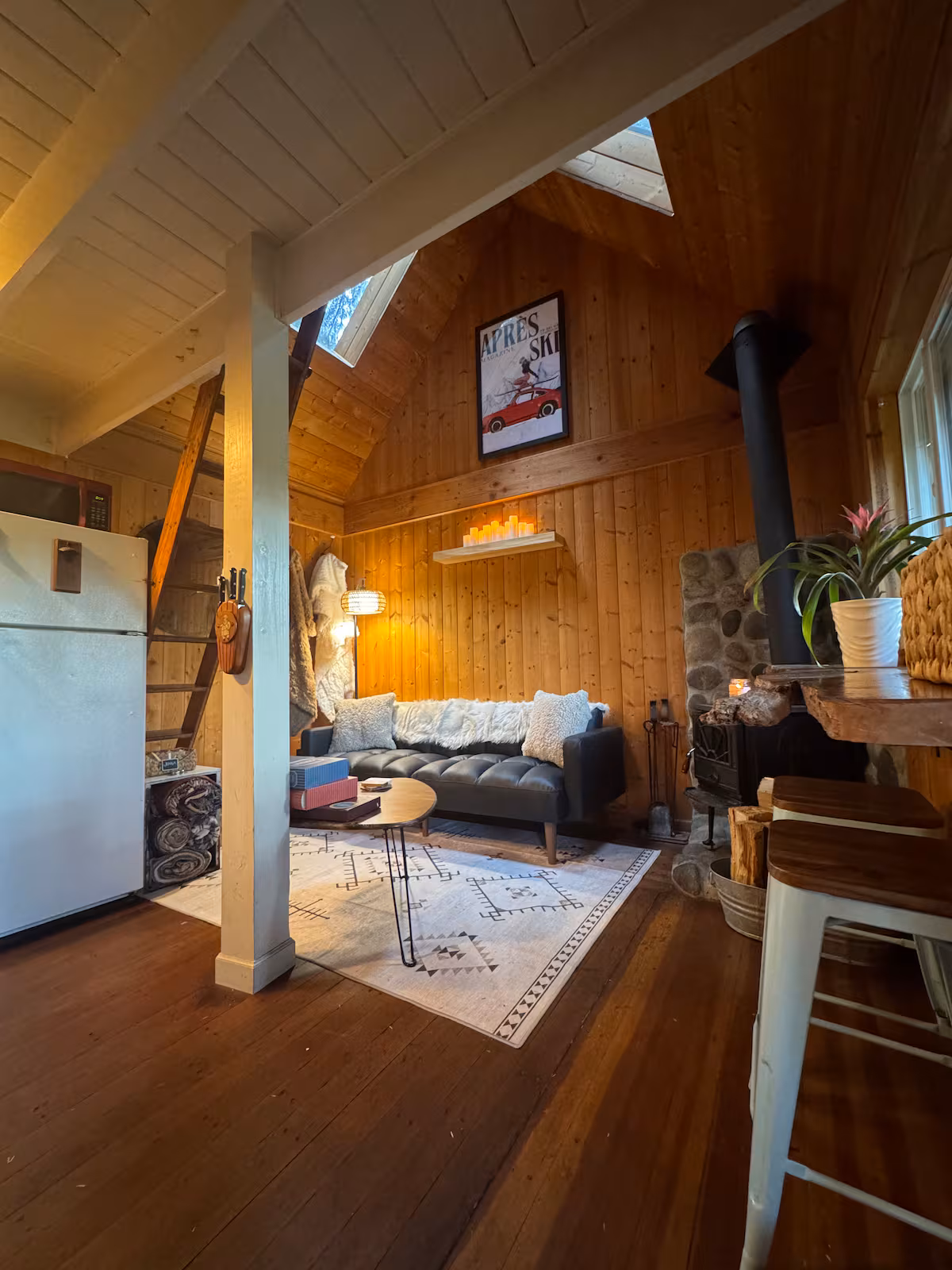 Cozy wooden cabin living room with a sofa, rug, and warm lighting.