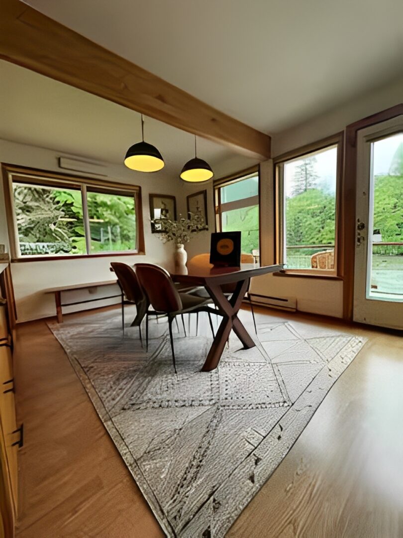 Cozy dining area with wooden table, cushioned bench, and large windows offering lush green views.