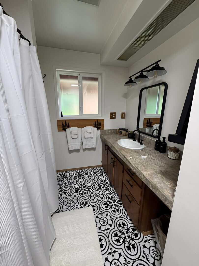 Bright bathroom with patterned floor tiles and wooden accents.