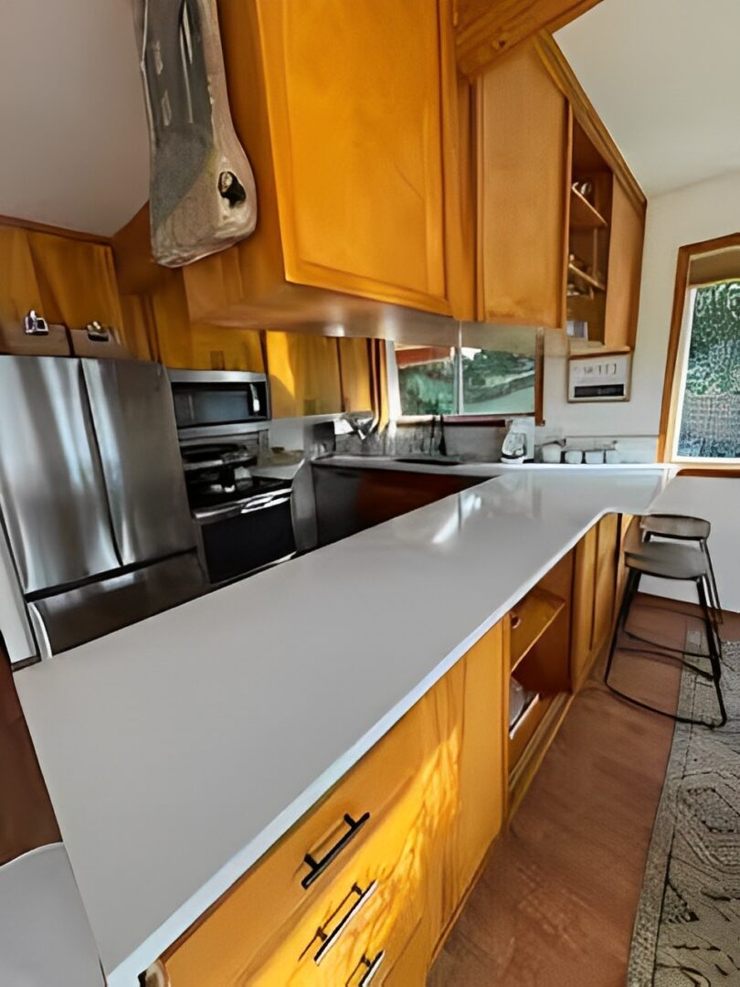 Modern kitchen with wooden cabinets and a long white countertop.