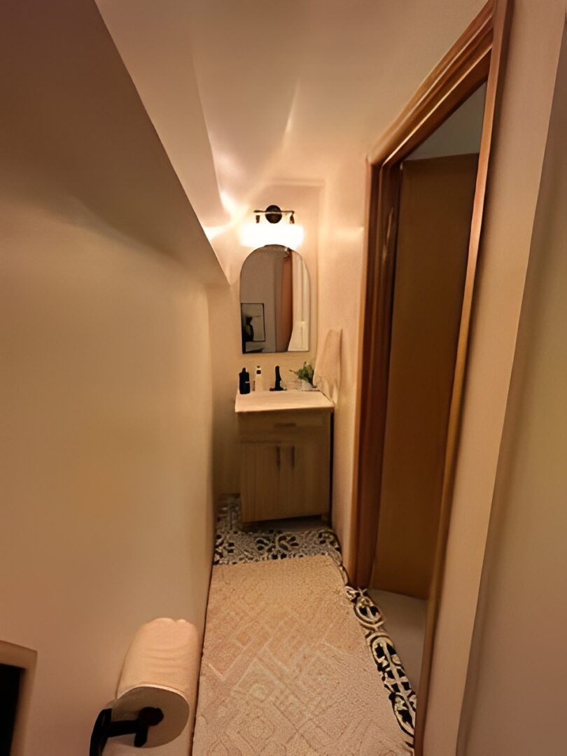 A narrow bathroom with a wooden vanity and mirror.