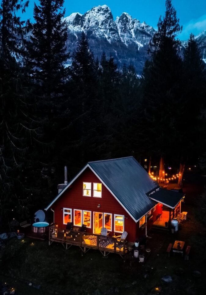 Cozy illuminated cabin in a forest at night.